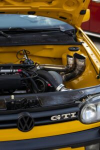 Vehicle engine bay showcasing performance modifications, including a turbocharger and custom piping, relevant to automotive maintenance and repair discussions.