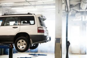 Vehicle being serviced in an automotive workshop, elevated on a lift, illustrating maintenance and repair processes relevant to the Martinsburg Service Center's expertise.