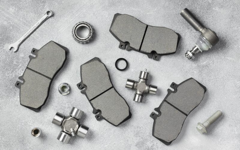 Different automotive brake pads and components arranged on a gray surface, relevant to brake system maintenance and issues like vibrations when braking.